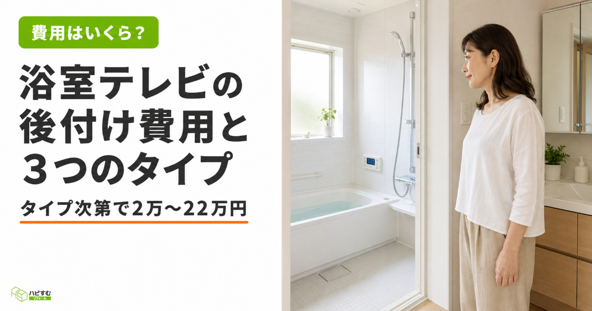 浴室の入り口から壁を見つめて考え込む白トップス姿の30代後半〜40代の日本人女性。タイトル「浴室テレビの後付け費用と3つのタイプ」とサブコピー「タイプ次第で2万〜22万円」を表示したハピすむのサムネ画像。