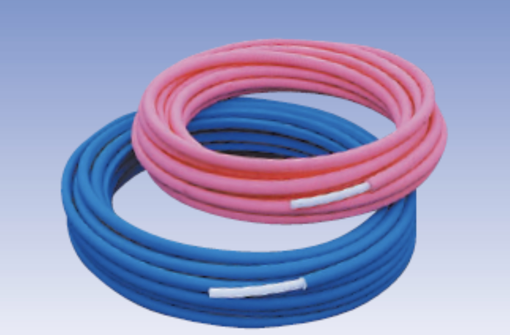 トイレの給水配管に使用されるクボタケミックス製の樹脂管（架橋ポリエチレン管）。巻かれた状態のピンク色と青色の2種類の管が並んでいる。近年主流の素材で、サビに強く、柔軟性があるため施工性に優れているのが特徴。