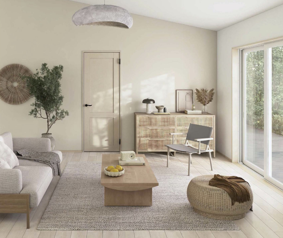 YKK APのドア「Smayell（スマエル）」を採用したリビングとトイレのコーディネート例。グレージュ系の落ち着いたトーンのドアが、木製のローテーブルやラタン調のスツール、ナチュラルなインテリアと調和し、開放的で洗練された空間を演出している。豊富な25カラーからインテリアに合わせて選べるデザイン性の高さを示す施工イメージ。